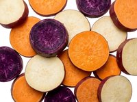 Colorful potato slices showing orange sweet potato, purple potato and white potato varieties arranged on white background for healthy cooking concepts.