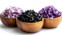 Three wooden bowls filled with colorful crystal gemstones including black obsidian and purple amethyst stones for healing and decoration.