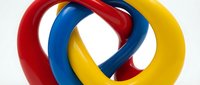 Colorful interlocked rings in red, blue and yellow forming abstract geometric sculpture on white background for modern design concepts.