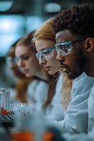 Diverse group of scientists in white lab coats working with test tubes and laboratory equipment. Focus on young researchers conducting chemical analysis.
