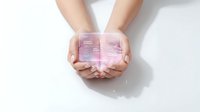 Hands gently holding glowing pink digital cube with futuristic holographic effects on white background for technology and innovation concepts.
