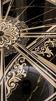 Ornate golden compass rose design on black marble surface with decorative baroque flourishes and intricate geometric patterns for luxury interior decor.