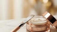 Luxury skincare cream jar with rose gold cap and applicator spatula on elegant vanity surface for premium beauty and cosmetic product marketing.