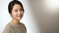 Young Asian woman smiling warmly in casual beige sweater against soft neutral background for lifestyle and portrait photography projects.