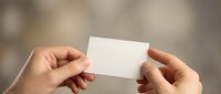 Hands holding blank white business card with soft blurred background for mockup and branding design projects.