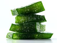 Fresh sliced aloe vera plant leaves stacked showing translucent green gel texture on white background, isolated for natural cosmetic and healthcare concepts.