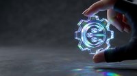 Close-up of hand holding glowing neon gear symbol with blue and cyan light effects on dark surface, representing technology, innovation, and digital engineering solutions.