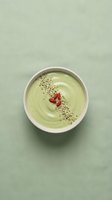 Green smoothie bowl with hemp seeds and goji berries in a white ceramic bowl, top view on a soft sage linen background. Healthy eating concept.