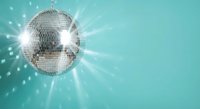 Shiny disco ball reflecting light beams against turquoise background creating sparkly party atmosphere for nightclub events and retro celebrations.