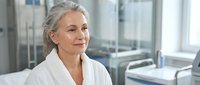 Confident mature Caucasian businesswoman with gray hair smiling in modern office environment. Professional corporate executive portrait for business content.