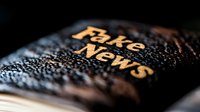Dramatic close-up of embroidered text on dark fabric with selective focus and shallow depth of field, highlighting golden thread stitching against textured background.