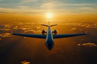 Private jet flying above golden clouds during dramatic sunset, rear view of luxury aircraft cruising at high altitude through glowing orange sky.
