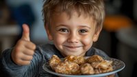 Cheerful young boy showing thumbs up while enjoying homemade baked cookies on plate, expressing joy and satisfaction with sweet treats during family baking time.