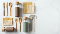 Flat lay arrangement of eco-friendly kitchen essentials including wooden utensils, reusable cloth napkins, bamboo containers, and sustainable drinkware on marble surface.