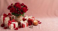 Romantic red roses bouquet with wrapped gift boxes and candles on pink background for Valentine's Day celebration and love occasions.