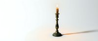 Vintage brass candlestick holder with burning candle flame on white background isolated for design projects and decorative concepts.