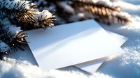 Blank white greeting cards nestled in fresh snow beside evergreen pine branches with warm golden sunlight creating peaceful winter holiday atmosphere.