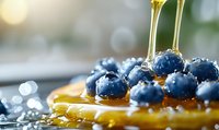Fresh blueberries on golden honey drizzle with morning dew drops, macro food photography showing sweet breakfast ingredients in natural light.