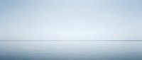 Calm minimalist seascape with still water and overcast sky, suitable for backgrounds, web design, and peaceful nature compositions.