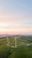 Aerial view of wind turbines on rolling green hills at sunset, generating renewable energy for sustainable power production and clean electricity generation.