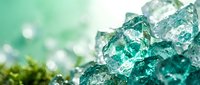 Crushed emerald green glass fragments with bokeh background and moss, suitable for texture overlays, design elements, and creative projects.