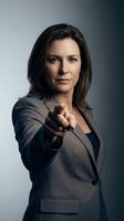 Confident businesswoman in gray suit pointing finger at camera with determined expression against gradient background for corporate leadership concepts.