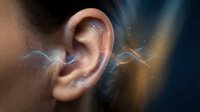 Close-up of human ear with glowing sound waves and audio frequencies visualization showing hearing, listening and acoustic perception concepts.