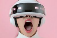 Young woman wearing virtual reality headset and headphones expressing excitement with open mouth against pink background. Modern gaming technology concept.