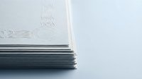 Stack of white embossed business cards with elegant letterpress design on clean background for corporate branding and professional identity materials.