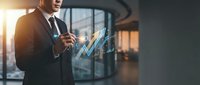 Professional businessman analyzing digital growth charts and data visualization in modern office environment for business strategy and financial planning.