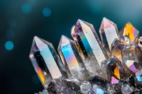 Iridescent crystal quartz points with rainbow reflections on dark background, macro photography showing natural mineral formation and light dispersion effects.