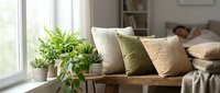 Cozy living room corner with wooden bench, decorative cushions in neutral tones, and potted green plant by bright window for home decor and interior design projects.