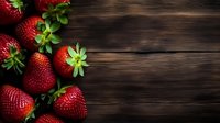 Fresh ripe strawberries scattered on dark wooden rustic background with copy space. Natural organic berries with green leaves for healthy eating.