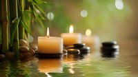 Zen spa composition with burning candles, bamboo and black stones reflected in calm water creating peaceful meditation atmosphere for wellness.