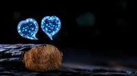 Glowing blue speech bubble hearts floating above wooden surface against dark background, creating magical romantic atmosphere for communication concept.