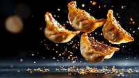 Flying golden crispy Asian dumplings with spices and seasonings falling on dark background, dramatic food photography for restaurant menu and advertising.
