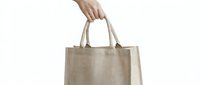 Hand holding natural beige linen eco-friendly reusable shopping bag isolated on white background for sustainable lifestyle and zero waste concept.