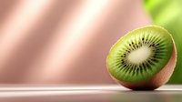Fresh kiwi fruit half showing green flesh and black seeds on pink background with natural lighting and copy space for healthy eating concepts.