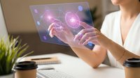Woman in white shirt interacting with holographic display showing glowing pink molecular structures and digital data visualization at modern office desk.