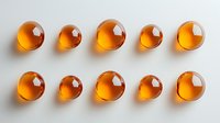Glowing amber liquid drops arranged in two rows on white surface create minimalist pattern with light and shadow play. Suitable for medical or cosmetic designs.