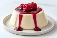 Creamy vanilla panna cotta topped with fresh raspberries and flowing raspberry sauce on white plate, elegant Italian dessert presentation for food photography.