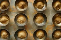 Overhead view of metal baking tins filled with different shades of flour or ground spices on rustic textured surface, perfect for food blogs and culinary publications.