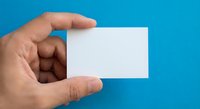 Hand holding blank white business card on blue background for mockup design and branding presentation.