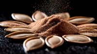 Copper metallic powder scattered in flower shape on black background with glitter particles and dramatic lighting creates luxurious cosmetic mood.