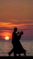 Romantic couple dancing silhouette against stunning ocean sunset with golden sky and calm waters creating intimate moment for wedding and love concepts.