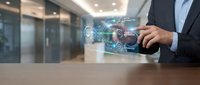 Businessman using tablet with digital holographic interface displaying data analytics and technology icons in modern office environment.