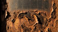 Rusty metal surface with heavy corrosion, peeling paint, and oxidized texture showing industrial decay and weathering effects suitable for grunge backgrounds.