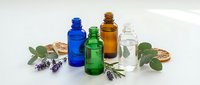 Essential oil bottles in blue green amber and clear glass with eucalyptus and lavender herbs for aromatherapy and natural wellness treatments.