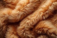 Close-up macro view of wavy golden brown fur texture showing soft fluffy animal hair strands in natural lighting, creating abstract organic pattern background.