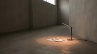 Minimalist interior space with concrete walls and floor, single illuminated desk lamp casting warm light on scattered papers, industrial architectural setting for design concepts.